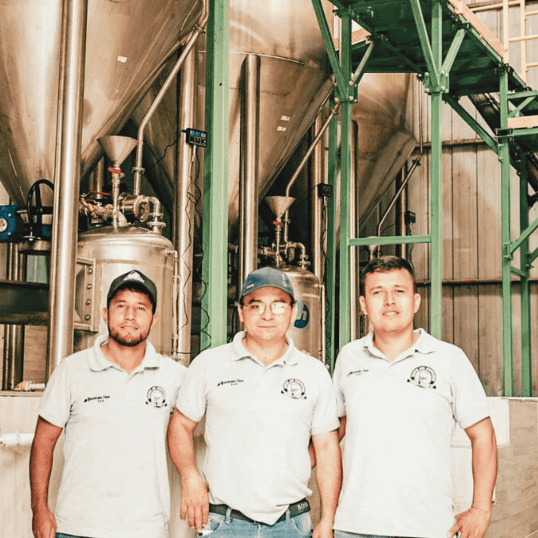 Wilton Benitez and friends standing in front of industrial coffee processing equipment
