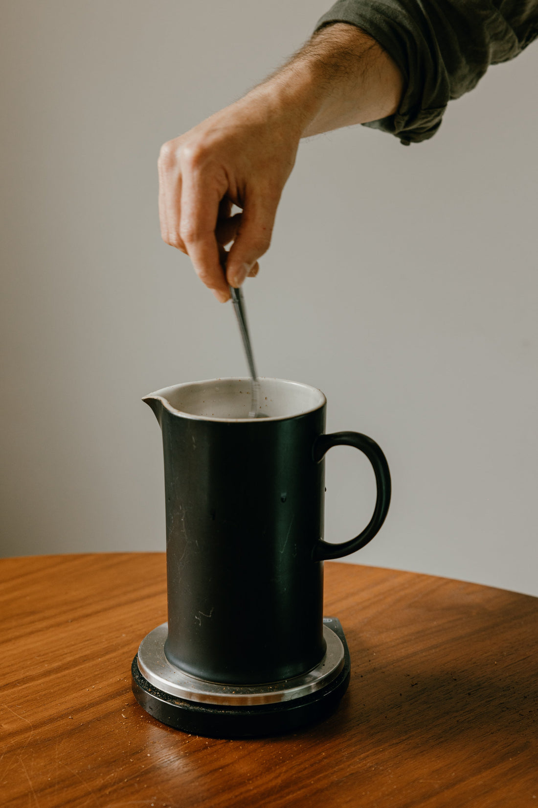 A hand stirring the coffee and hot water in a cafetiere