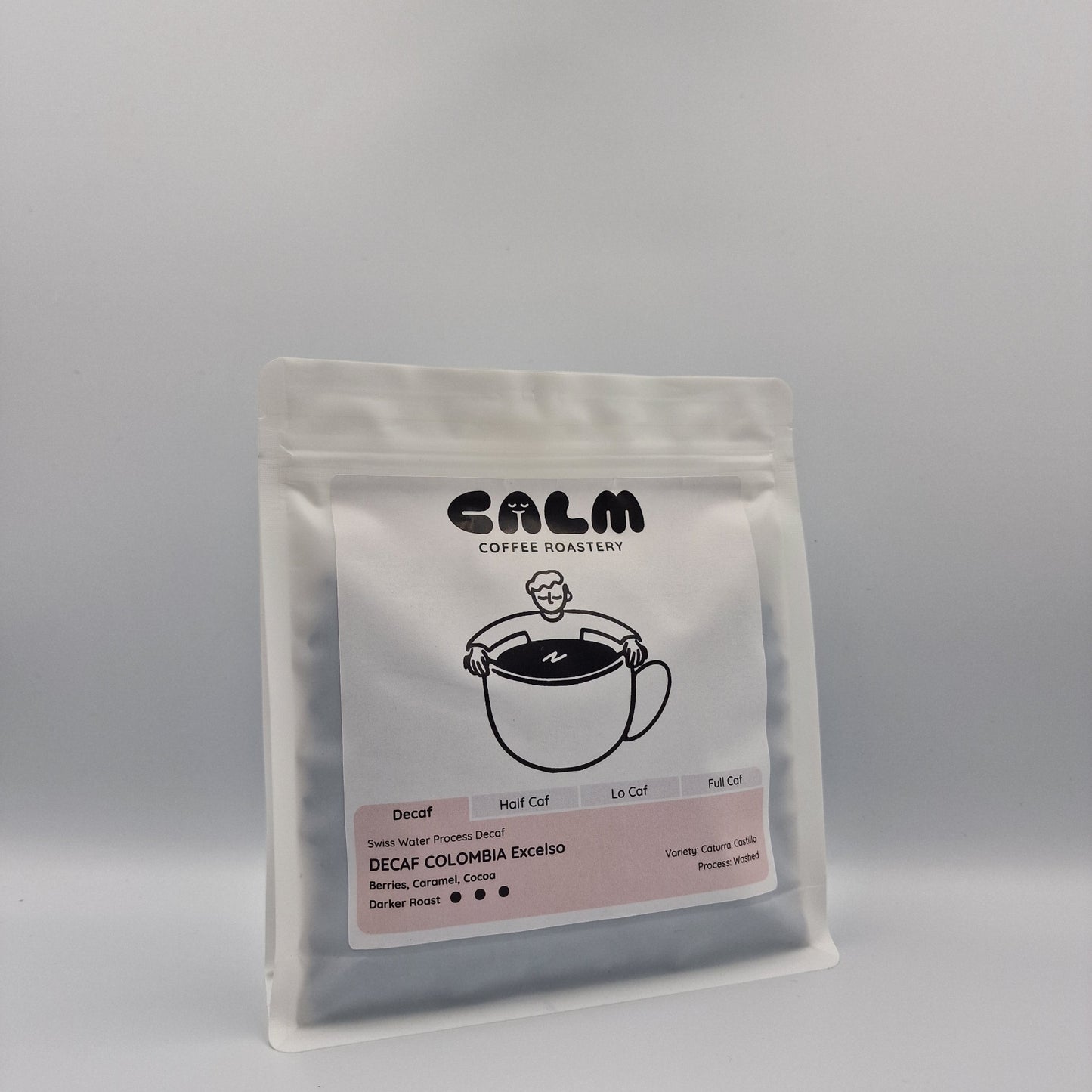 Angle view of Decaf Colombia Excelso coffee bag with Calm Coffee Roastery branding, highlighting darker roast and tasting notes of berries, caramel, and cocoa.